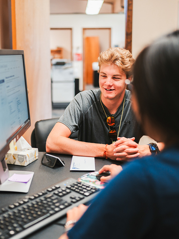 Students sit on a rock wall together, chatting.
